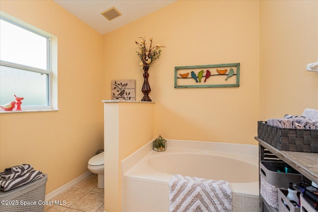 bathroom with toilet, tile patterned flooring, and tiled tub