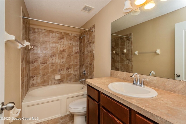 full bathroom with toilet, vanity, and tiled shower / bath