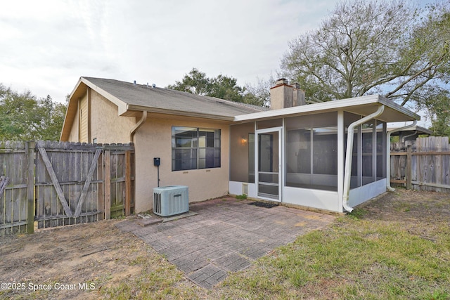 back of house featuring a patio, a sunroom, central AC, and a lawn