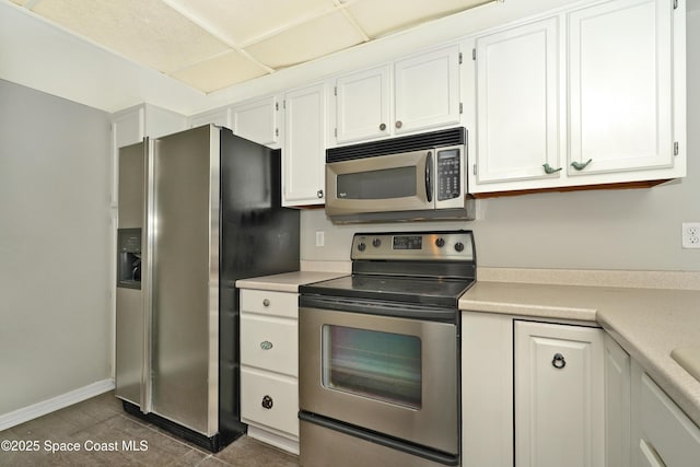 kitchen with white cabinetry, stainless steel appliances, and dark tile patterned flooring