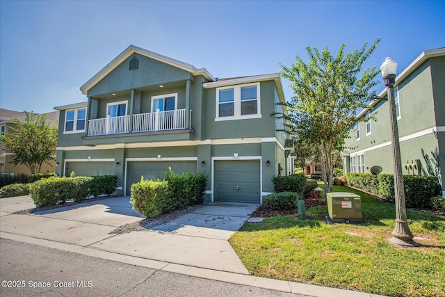 multi unit property with a front yard, a balcony, and a garage