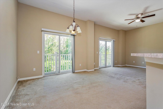 carpeted empty room featuring ceiling fan with notable chandelier