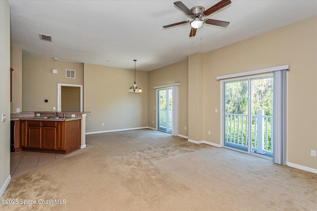 unfurnished living room with sink, ceiling fan with notable chandelier, and light carpet