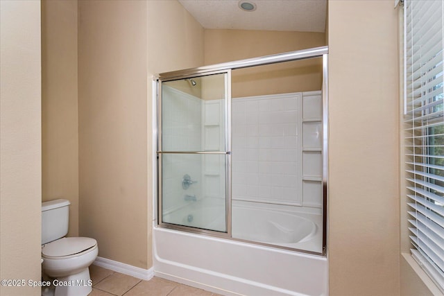 bathroom featuring toilet, enclosed tub / shower combo, and tile patterned flooring