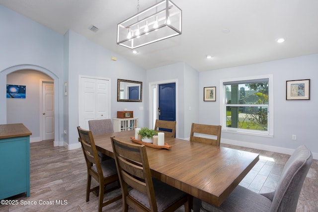 dining space featuring lofted ceiling, light hardwood / wood-style floors, and a notable chandelier