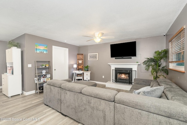 living room with a textured ceiling, light hardwood / wood-style flooring, and ceiling fan