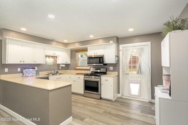 kitchen featuring sink, white cabinetry, appliances with stainless steel finishes, and kitchen peninsula