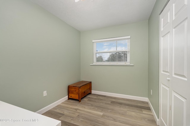 bedroom with light hardwood / wood-style floors, a textured ceiling, and a closet