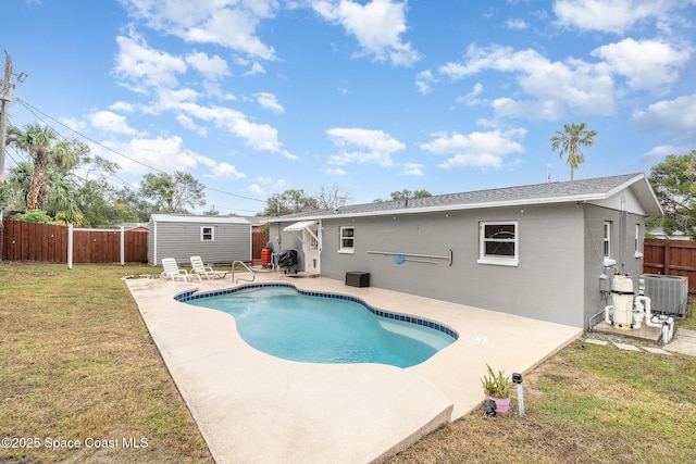 view of pool with a patio area, a yard, central AC unit, and a storage unit