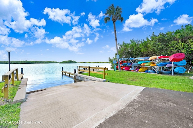 view of dock with a water view and a lawn