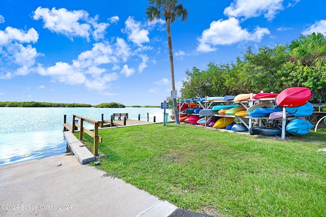 view of dock with a yard and a water view