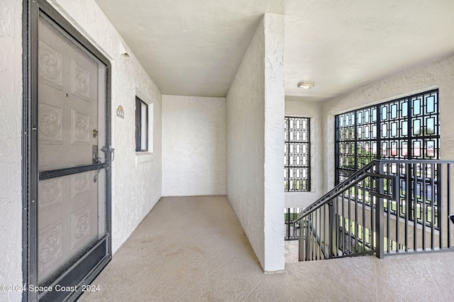 hallway with an upstairs landing and a textured wall