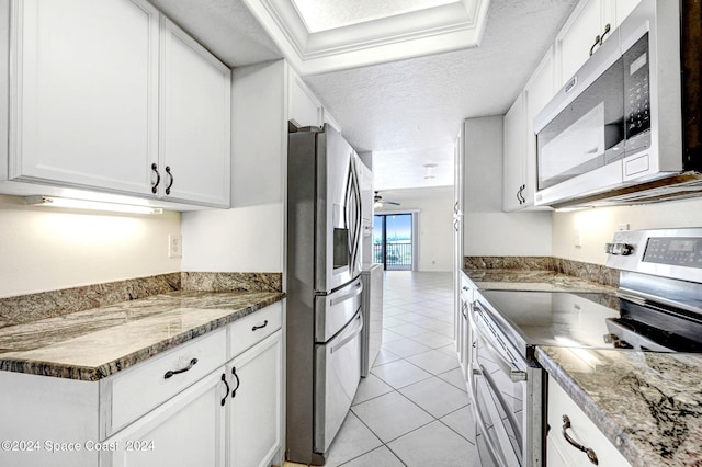 kitchen featuring light tile patterned floors, a textured ceiling, appliances with stainless steel finishes, and white cabinets