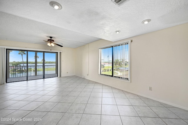 spare room featuring visible vents, a water view, light tile patterned floors, a textured ceiling, and a ceiling fan