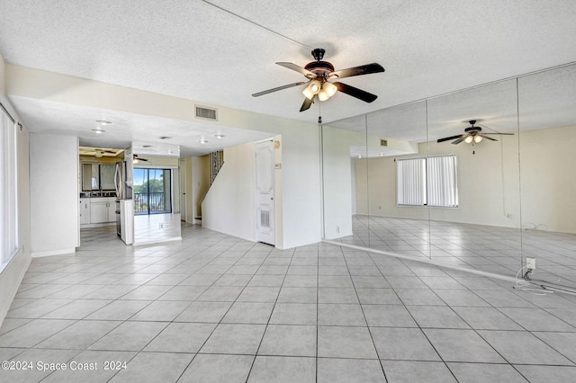 unfurnished living room with light tile patterned floors, visible vents, a textured ceiling, and ceiling fan