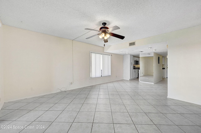 spare room with ceiling fan, a textured ceiling, and light tile patterned floors