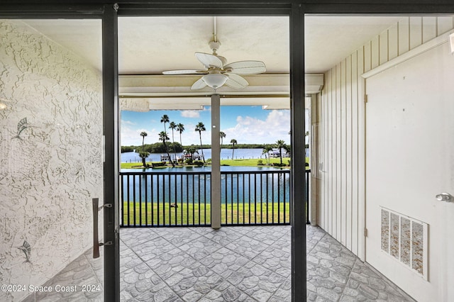 sunroom / solarium with ceiling fan and a water view