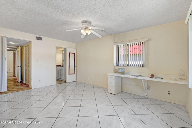 interior space with ceiling fan, built in desk, a textured ceiling, and light tile patterned floors