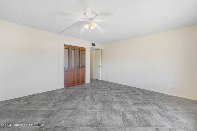 spare room featuring visible vents, baseboards, a textured ceiling, and a ceiling fan