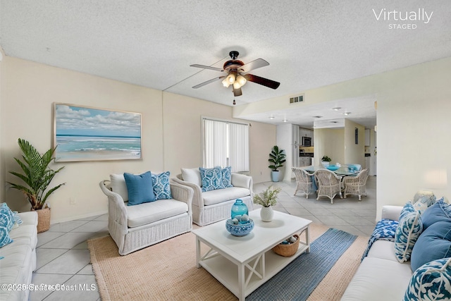 living area featuring light tile patterned floors, visible vents, a textured ceiling, and ceiling fan