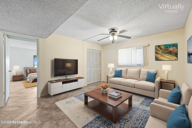 living room featuring light tile patterned floors, a textured ceiling, and ceiling fan