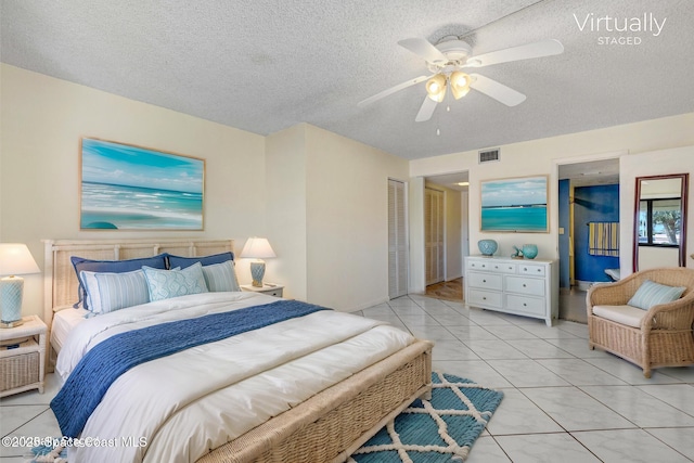 bedroom featuring visible vents, a textured ceiling, a closet, light tile patterned flooring, and ceiling fan