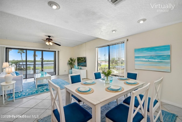 dining space featuring visible vents, a textured ceiling, light tile patterned flooring, baseboards, and ceiling fan