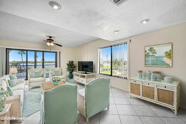 living room with light tile patterned floors, plenty of natural light, ceiling fan, and a water view