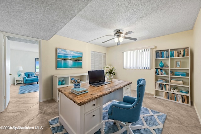 home office featuring light tile patterned floors, baseboards, a textured ceiling, and ceiling fan