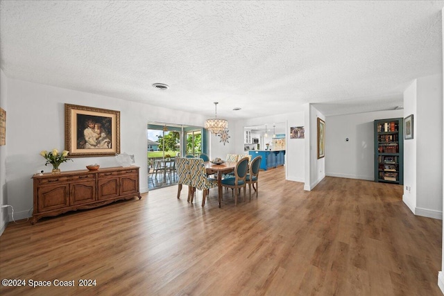 dining area featuring an inviting chandelier, wood-type flooring, and a textured ceiling