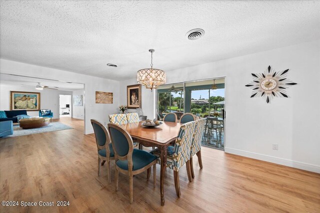 dining area featuring ceiling fan with notable chandelier, light hardwood / wood-style floors, and a textured ceiling