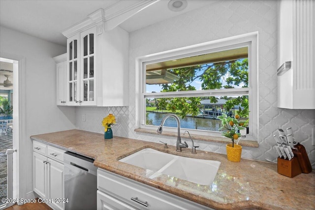 kitchen featuring white cabinetry, dishwasher, sink, light stone counters, and a water view