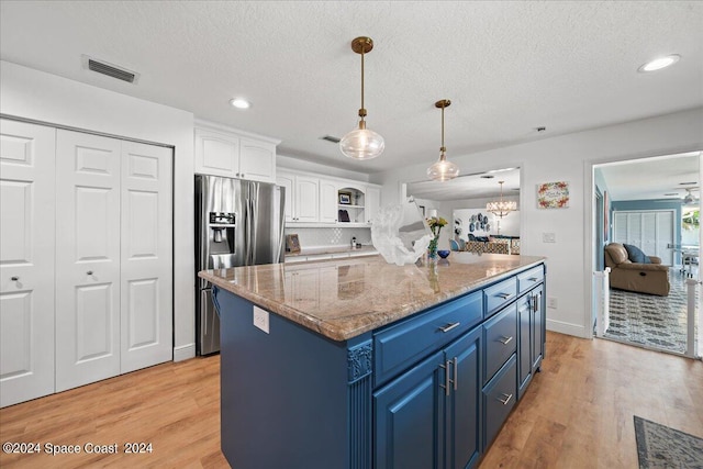 kitchen with pendant lighting, blue cabinets, white cabinetry, stainless steel fridge with ice dispenser, and light stone countertops