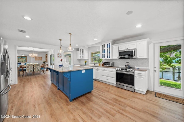 kitchen featuring decorative light fixtures, a center island, stainless steel appliances, light stone countertops, and white cabinets