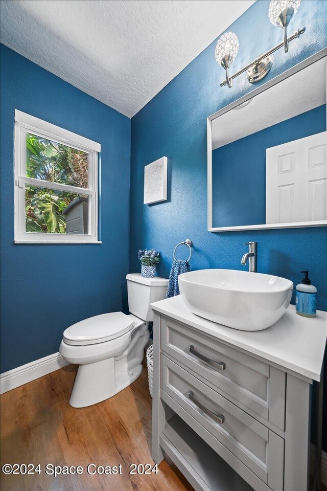 bathroom featuring vanity, hardwood / wood-style floors, a textured ceiling, and toilet