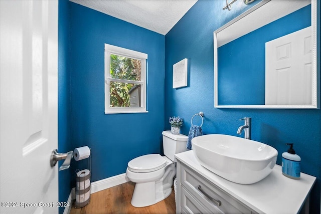 bathroom with vanity, toilet, hardwood / wood-style floors, and a textured ceiling