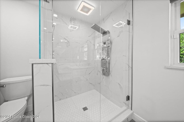 bathroom featuring a shower with shower door and toilet