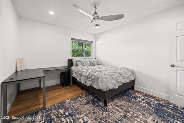 bedroom featuring ceiling fan, hardwood / wood-style floors, and a textured ceiling