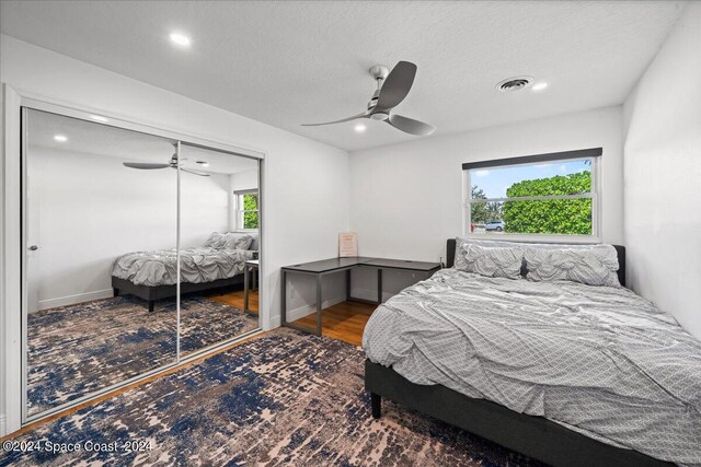 bedroom featuring wood-type flooring, ceiling fan, a textured ceiling, and a closet