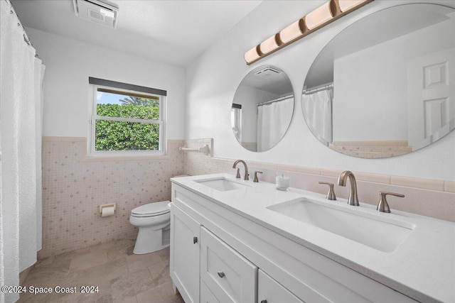 bathroom with tile walls, vanity, and toilet