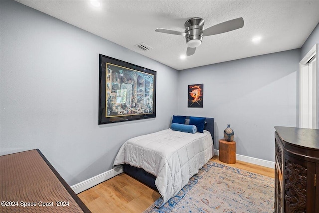 bedroom featuring hardwood / wood-style flooring, ceiling fan, and a textured ceiling