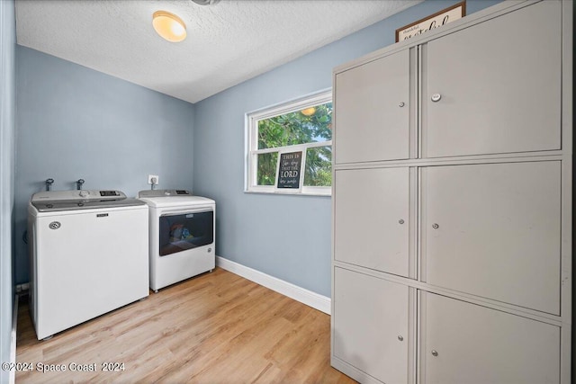 laundry room featuring cabinets, a textured ceiling, independent washer and dryer, and light hardwood / wood-style flooring