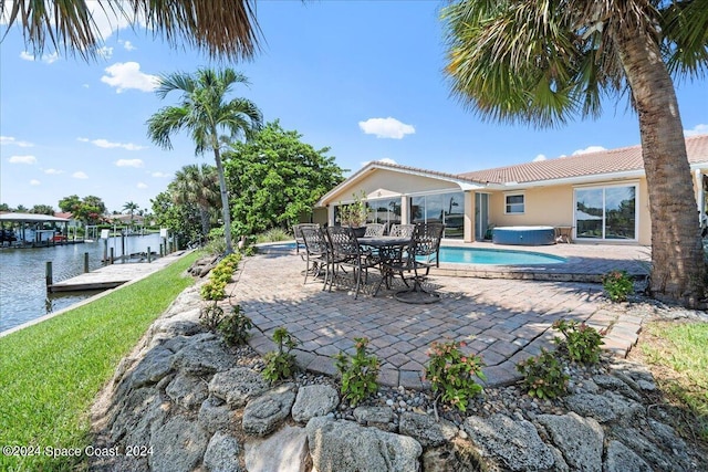 view of pool with a jacuzzi, a dock, a patio, and a water view