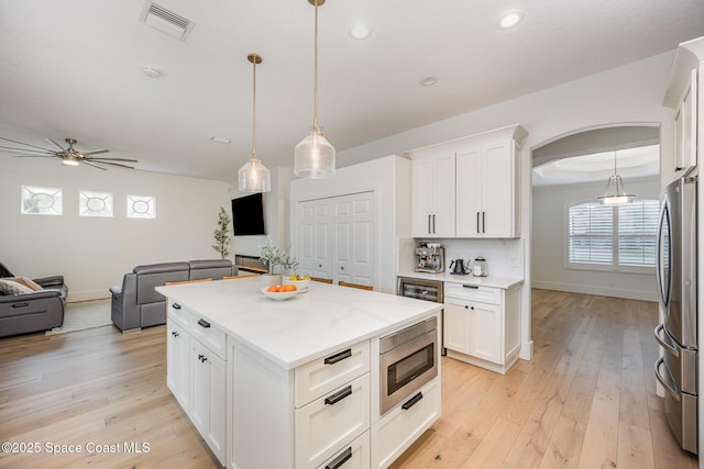 kitchen with white cabinetry, stainless steel appliances, a center island, and hanging light fixtures