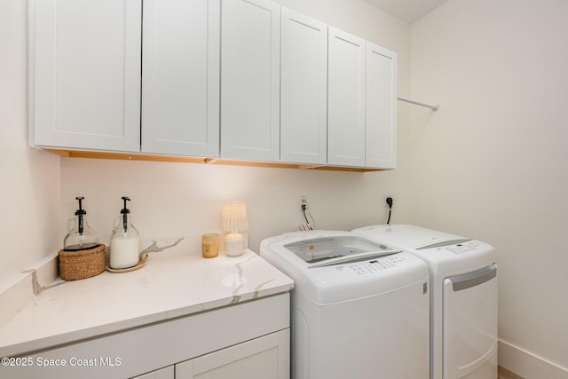 clothes washing area featuring cabinets and washer and dryer