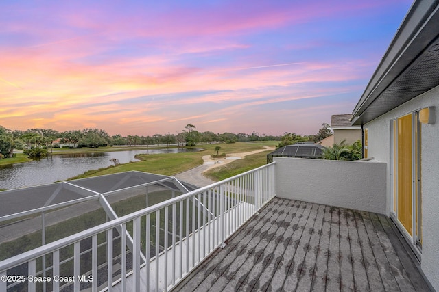 deck at dusk with glass enclosure and a water view