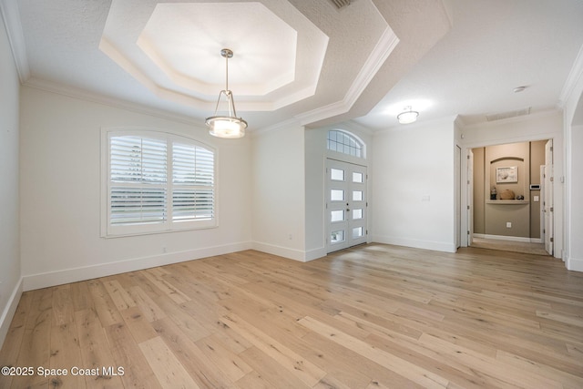 spare room featuring ornamental molding, a raised ceiling, and light hardwood / wood-style flooring