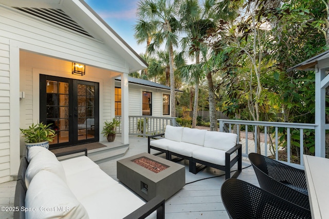 wooden deck featuring french doors and an outdoor living space with a fire pit