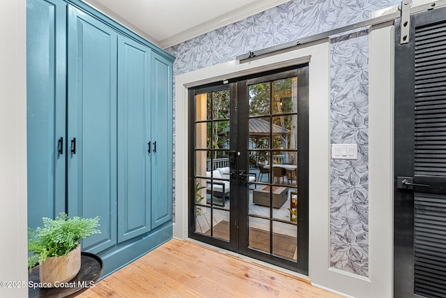 doorway featuring crown molding, a barn door, light wood-type flooring, and french doors