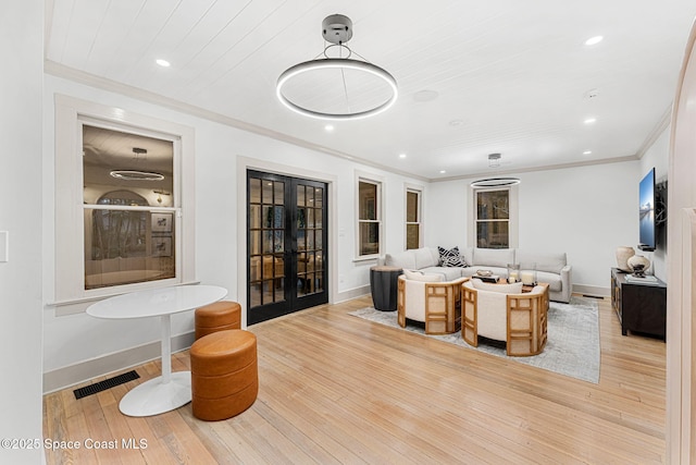 living room featuring crown molding, light hardwood / wood-style flooring, and french doors